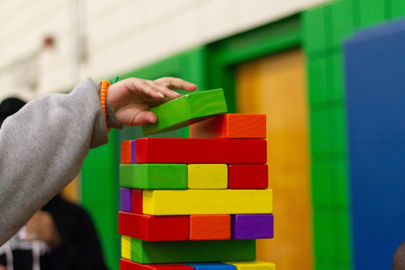 Hands stacking wooden blocks during a learning activity